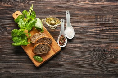 Kesilmiş ekmek, taze fesleğen, zeytinyağı ve baharat masada ahşap tahta