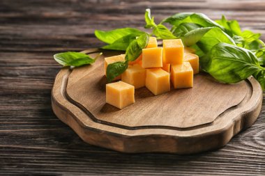 Ahşap tahta kesilmiş peynir ve taze fesleğen tablo ile