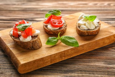 Mozzarella peyniri, domates ve fesleğen ahşap tahta üzerinde lezzetli sandviçler