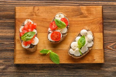 Mozzarella peyniri, domates ve fesleğen ahşap tahta üzerinde lezzetli sandviçler