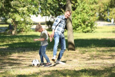Mutlu baba ve oğul parkta futbol oynarken