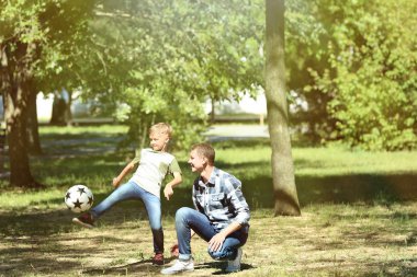 Mutlu baba ve oğul parkta futbol oynarken
