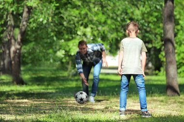 Mutlu baba ve oğul parkta futbol oynarken