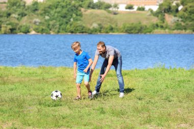Mutlu baba ve oğul Nehri yakınında futbol oynarken