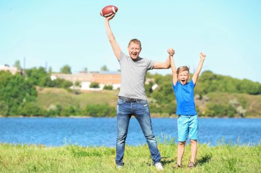 Mutlu baba ve oğul Nehri yakınında rugby topu ile