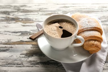 Lezzetli kruvasan ve ahşap arka plan üzerinde içecek fincan