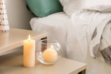Burning wax candles on table in bedroom clipart