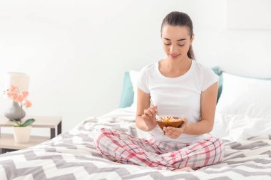 Güzel genç kadın yatak odasında kahvaltı için lezzetli yulaf ezmesi