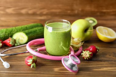 Bir bardak taze lezzetli smoothie malzemeler ve ahşap arka plan üzerinde stetoskop ile. Sağlık kavramı