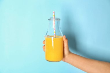 Renk arka plan üzerinde lezzetli güler yüzlü ile şişe tutan el