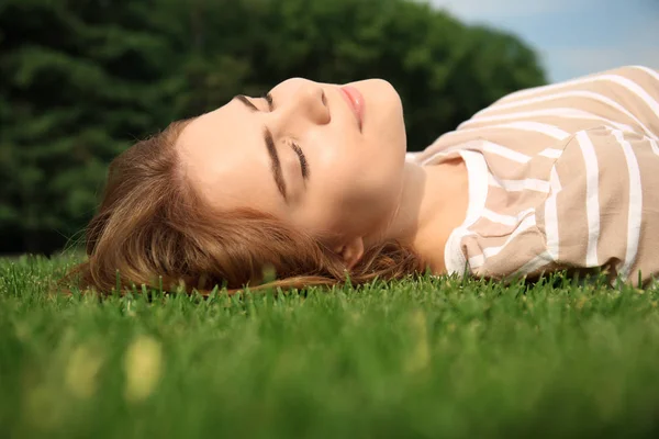 Genç kadın açık havada yeşil çimenlerin üzerinde rahatlatıcı
