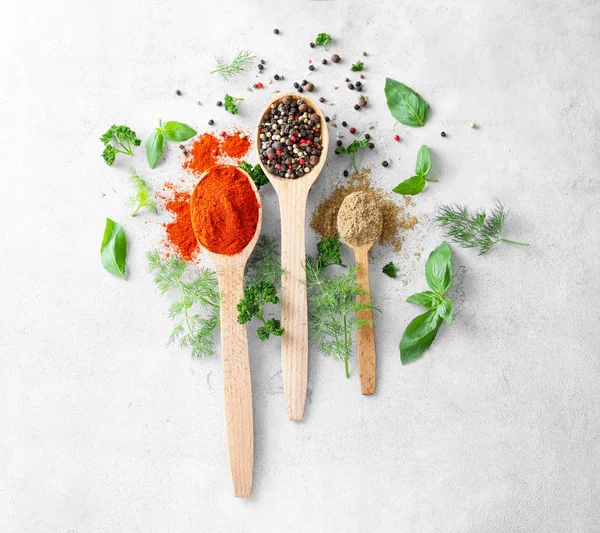 Tahta kaşık ile taze otlar ve gri dokulu arka plan üzerinde kuru baharat