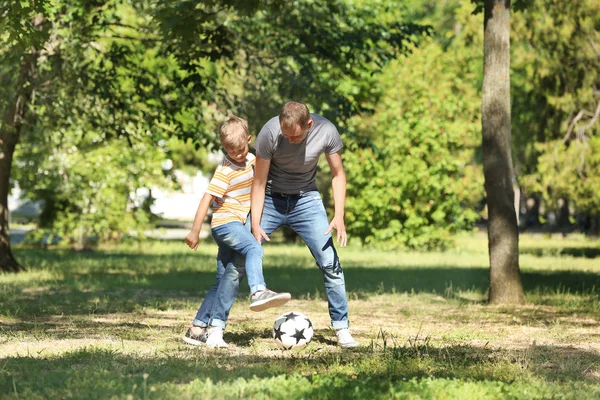 Happy father and son playing football in park