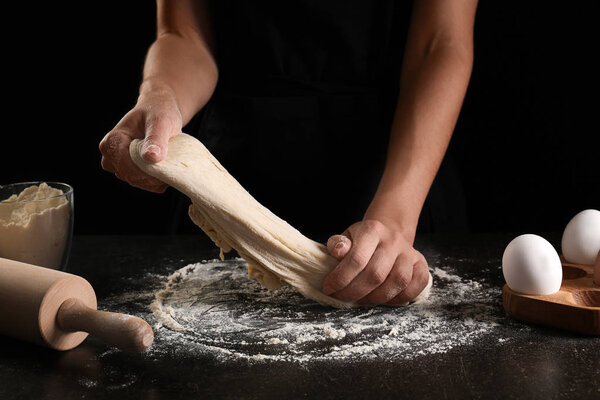 Woman kneading dough for bakery on kitchen table