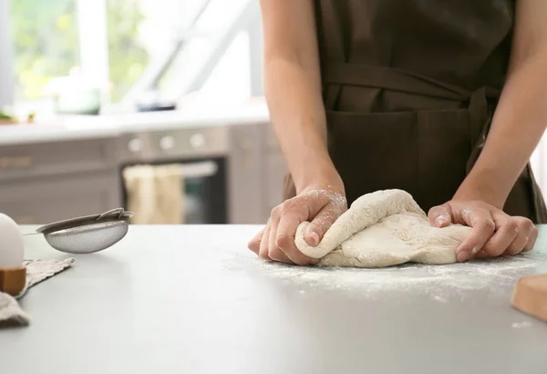 Woman kneading dough for bakery on kitchen table