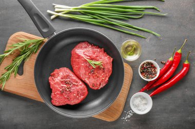 Çiğ et, otlar ve baharatlar ahşap tahta üzerinde tava