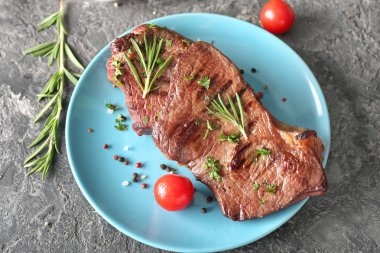 Lezzetli biftek, otlar, domates ve baharat grunge tablo ile plaka