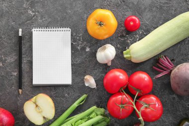 Gri arka plan üstünde defter ile çeşitli sağlıklı ürünler