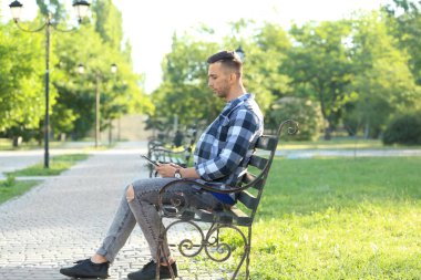 Yakışıklı adam parkta bankta oturan tablet bilgisayar ile