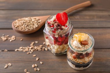 Lezzetli yulaf ezmesi tatlılar taze meyveleri ve ahşap masa üzerinde cam kavanozlara ballı