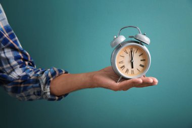 Çalar saat renk arka plan üzerinde tutan adam. Zaman yönetimi kavramı