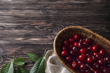 Olgun kiraz ahşap arka plan ile sepet kamışı kase