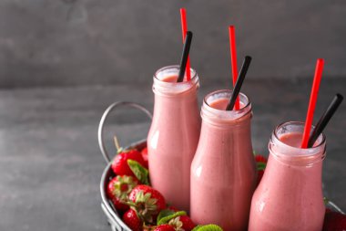 Sepet şişe lezzetli güler yüzlü ve gri masada çilek ile