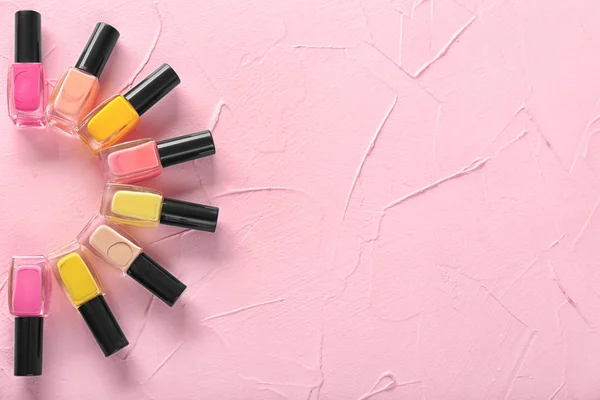 Bottles of nail polishes on color background