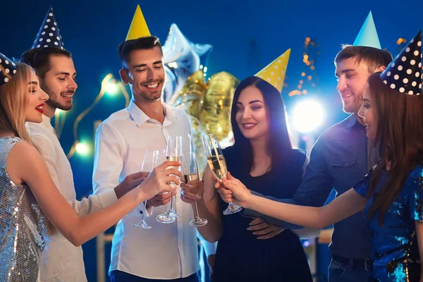 Young people with glasses of champagne at birthday party in club