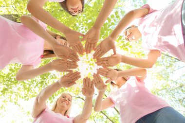 Güzel kadınlar farklı yaş ile birlikte açık havada ellerini koyarak pembe kurdeleler. Meme kanseri kavramı