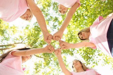 Güzel kadınlar farklı yaş ile birlikte açık havada ellerini koyarak pembe kurdeleler. Meme kanseri kavramı