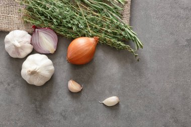 Sarımsak ve soğan gri dokulu arka plan üzerinde taze otlar