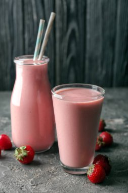 Cam ve gri masada çilek güler yüzlü şişesiyle