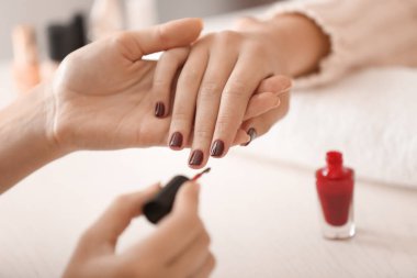 Genç bir kadın güzellik salonunda profesyonel manikür yaptırıyor.
