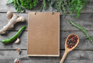 Taze otlar, baharatlar ve ahşap arka plan üstünde defter ile kompozisyon