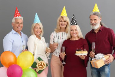 Olgun insanlar lezzetli pasta ve şampanya gri arka plan üzerinde Doğum günü kutluyor