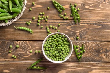 Ahşap masa üzerinde yeşil bezelye ile kase