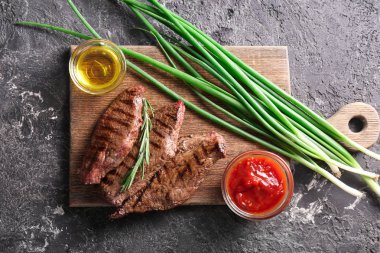 Yeşil soğan, yağ ve sos ahşap tahta üzerinde lezzetli ızgara et