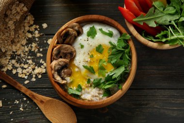 Lezzetli yulaf ezmesi, otlar ve ahşap masa üstünde yumurta ile kase