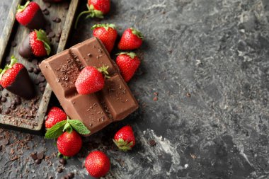 Gri dokulu arka plan üzerinde çikolata ile taze olgun çilek