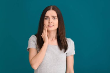 Arka planda diş ağrısı çeken genç bir kadın.