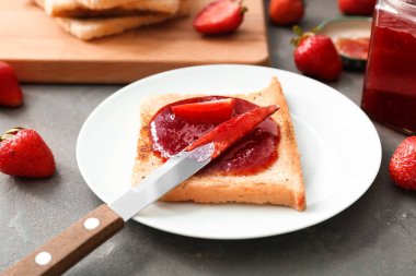 Tost ve gri masada çilek reçeli ile plaka