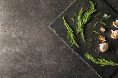 Taze biberiye, baharat ve koyu arka plan üzerine sarımsak ile kayrak plaka