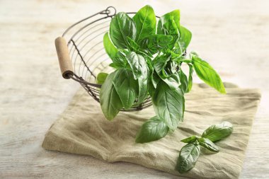 Ahşap masa üzerinde taze Fesleğenli metal sepet