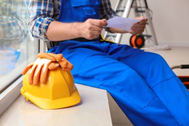 Devre şeması, eldiven ve kask kapalı pencere kenarında oturan elektrikçi