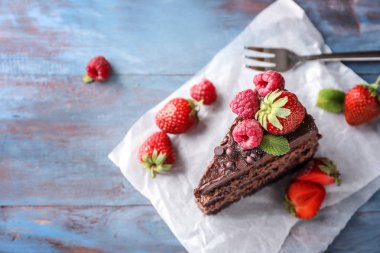 Ahşap masa üzerinde meyveleri lezzetli çikolatalı kek parçası