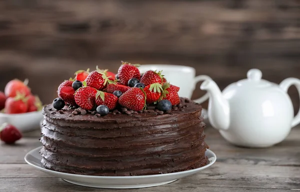 Tasty chocolate cake decorated with strawberry and blueberry on wooden table