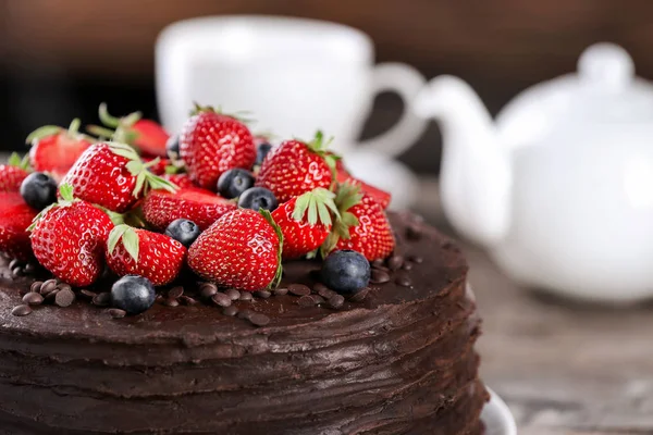 Tasty chocolate cake decorated with strawberry and blueberry, closeup