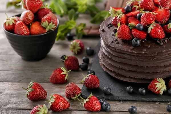 Tasty chocolate cake decorated with strawberry and blueberry on wooden table