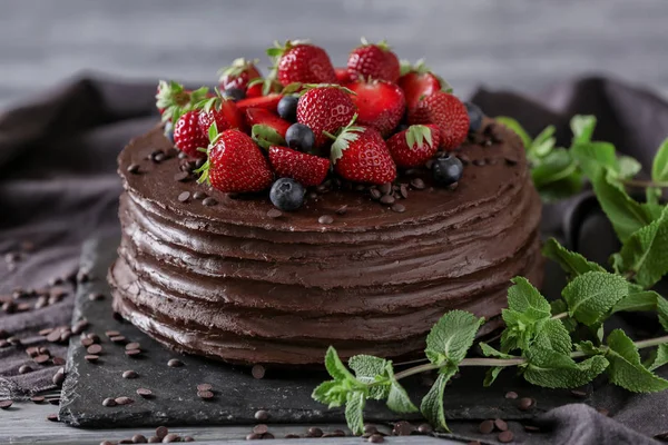 Tasty chocolate cake decorated with strawberry and blueberry on table